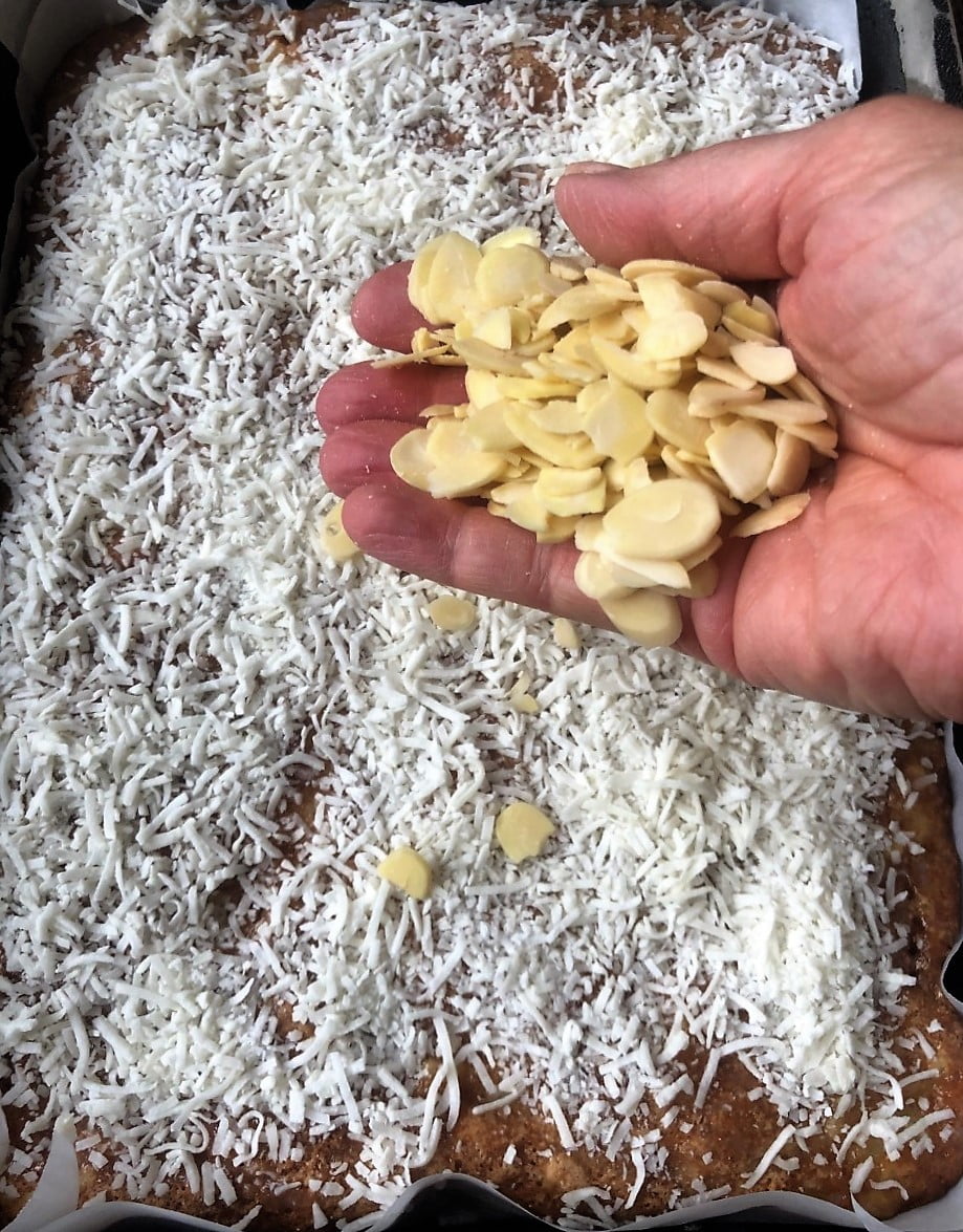 Sliced almonds top the coconut layer